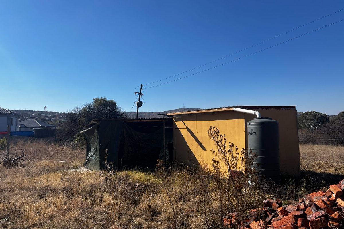 A view of a small utility structure on a vacant residential plot, featuring a water storage tank and basic exterior wall finishes.