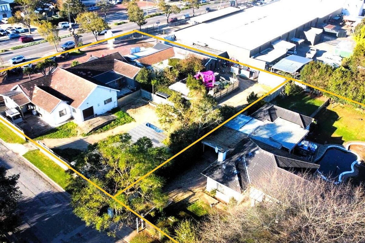 Aerial view of a commercial property site featuring multiple buildings, a swimming pool, paved areas, and established garden grounds with boundary fencing.