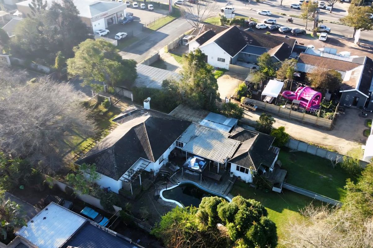 Aerial view of the commercial property featuring a swimming pool, timber decking, and surrounding garden area with established trees.