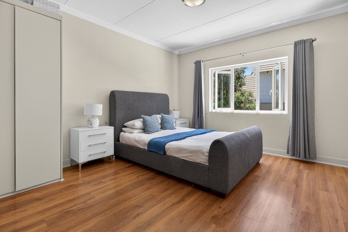 A well-maintained bedroom featuring laminate flooring, a built-in wardrobe, and a casement window providing natural light.
