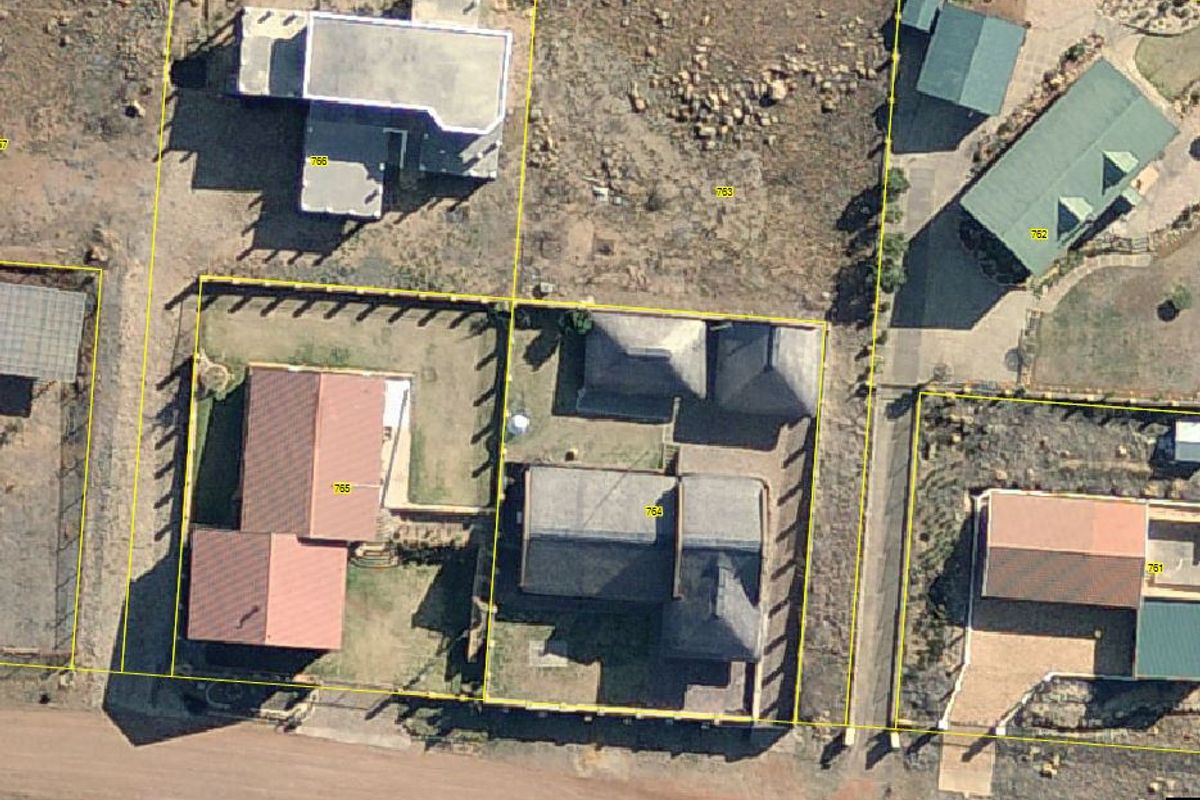 Aerial view of the property showing the building layout, roof structure, surrounding garden, and boundary fencing within the estate.