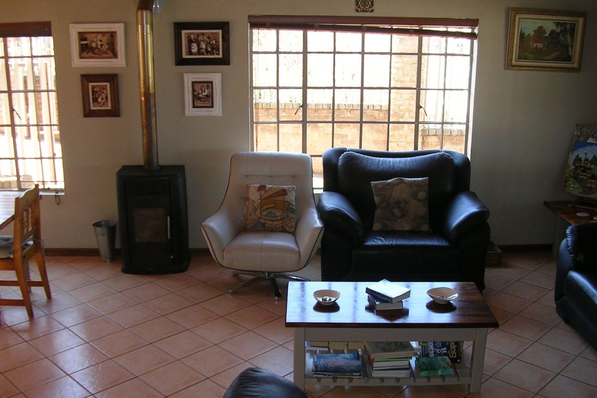 A cozy living room featuring tiled flooring, a freestanding fireplace, and large grid-pattern windows that provide natural light.