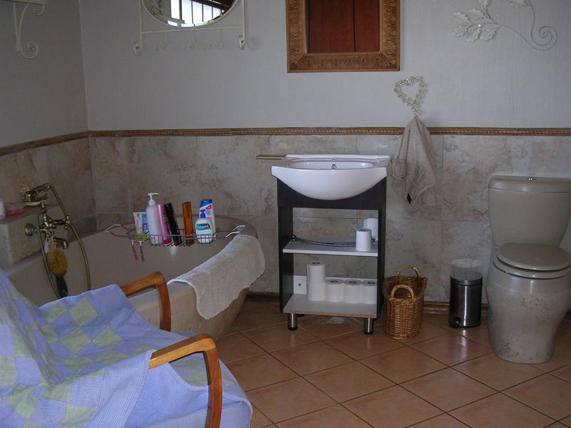 A dated bathroom featuring a bathtub, pedestal-style basin, and toilet with neutral wall and floor tiling.