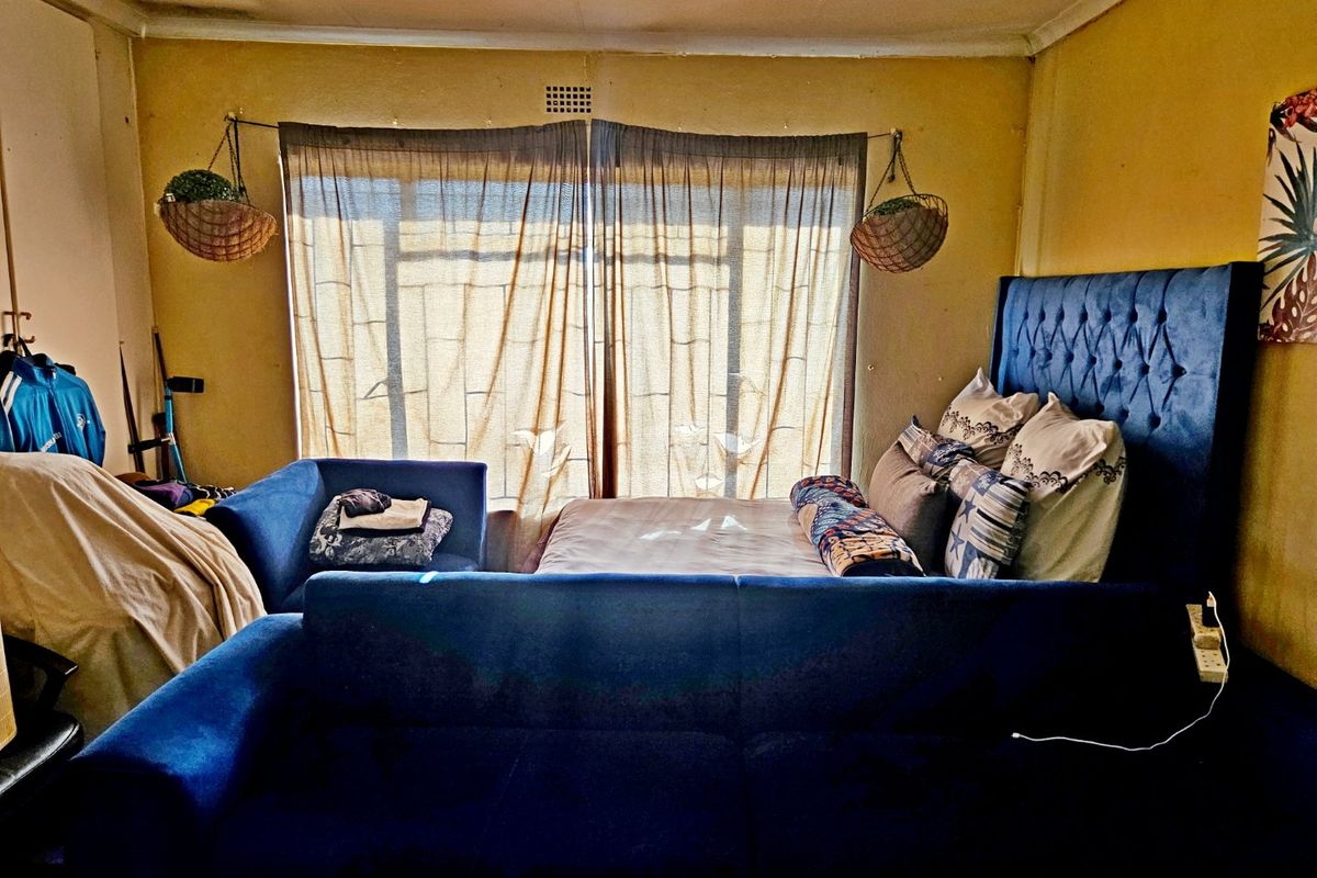A bedroom featuring a sliding glass door and ceiling fan, currently requiring cosmetic updates to the walls and ceiling finishes.