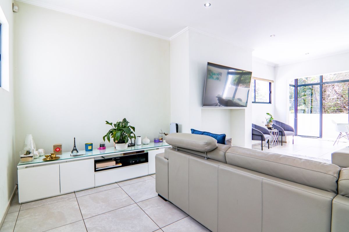 A bright and spacious living room featuring neutral tiled flooring, recessed lighting, and large sliding glass doors that provide ample natural light.