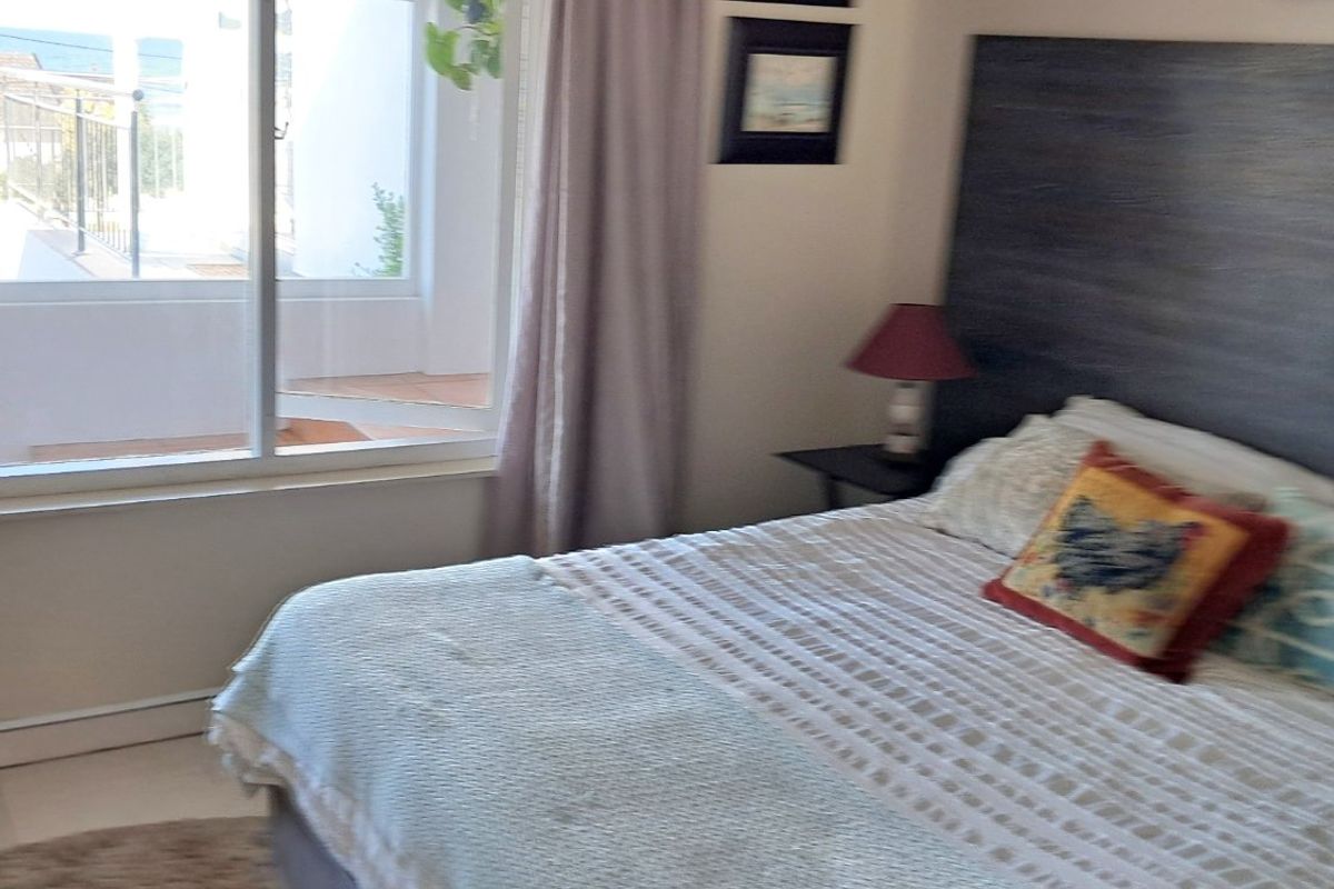 A bedroom featuring a built-in headboard and a sliding glass door providing access to an outdoor balcony area.