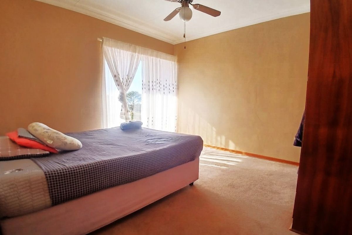 A standard bedroom featuring carpeted flooring, a ceiling fan, and coved cornicing, offering a neutral space ready for personalization.