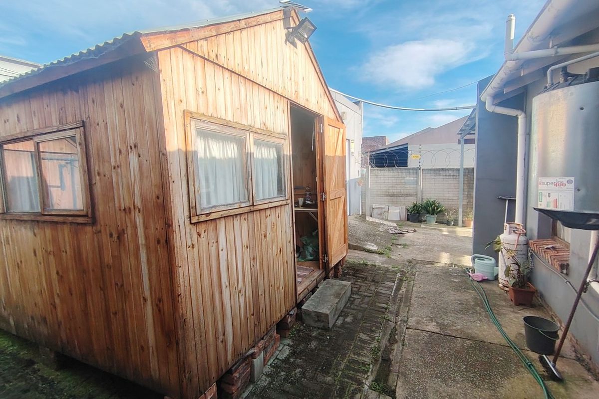 Rear yard area featuring a timber shed structure, concrete paving, and perimeter security fencing with an external solar geyser unit.