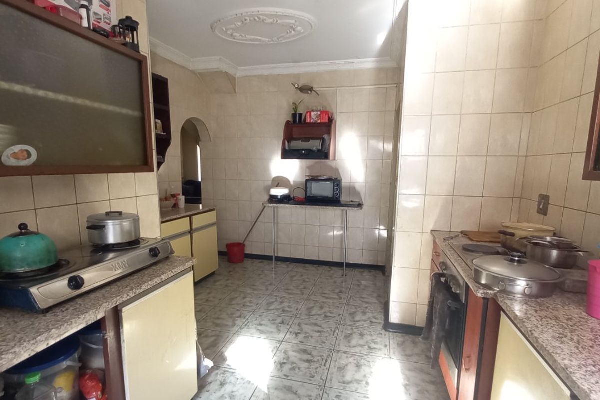 A dated kitchen featuring tiled walls and flooring, granite countertops, and built-in cabinetry, offering significant potential for a modern renovation.