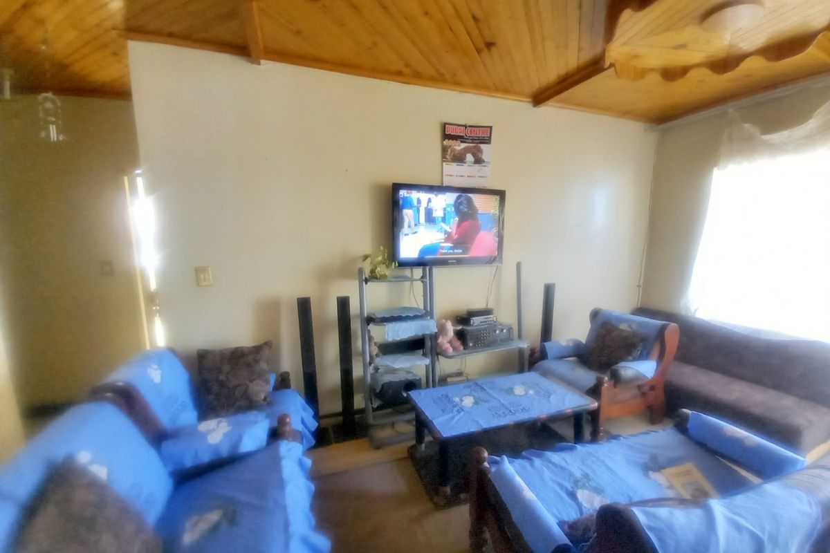A living room featuring a distinctive timber-clad vaulted ceiling with decorative wooden trim, providing a rustic aesthetic.