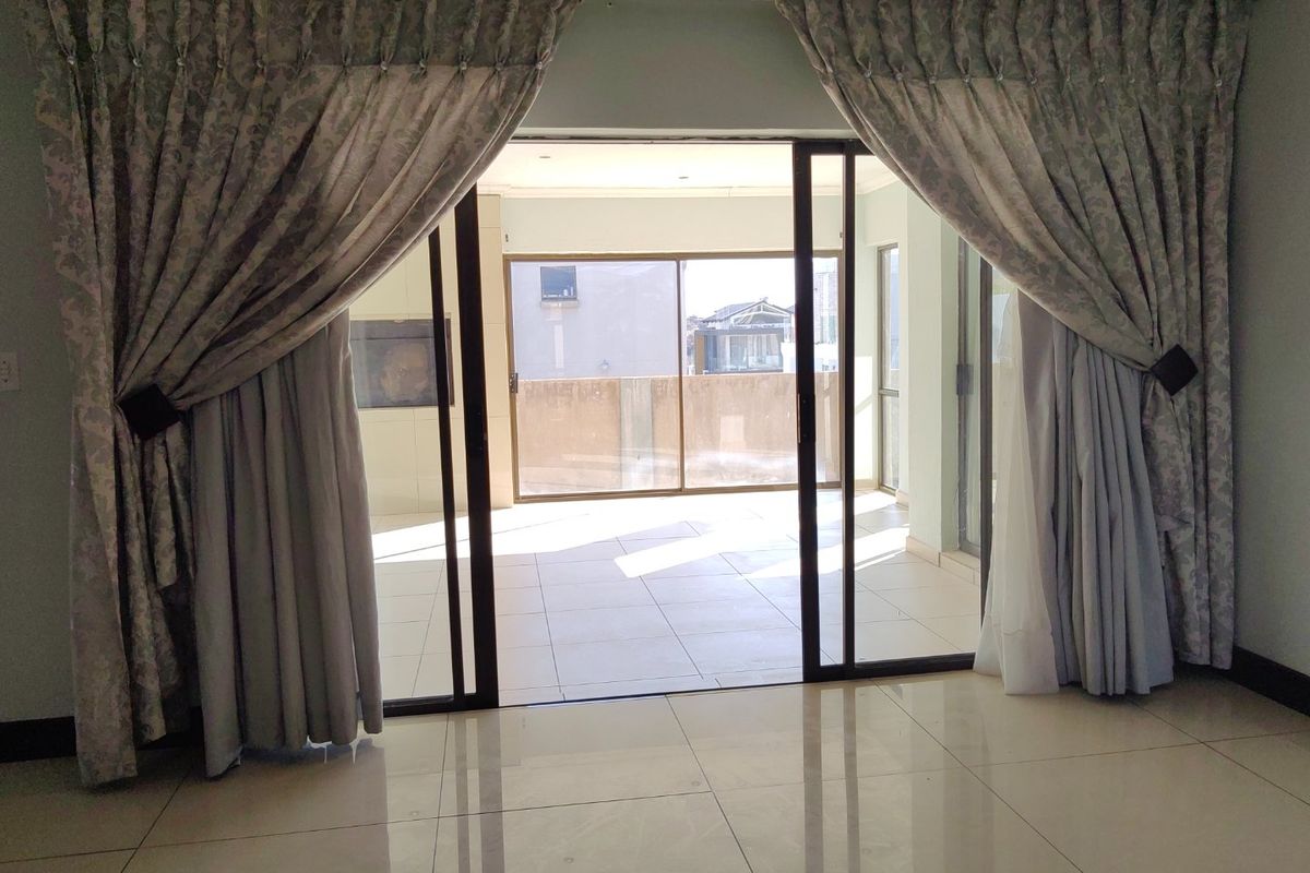 Spacious living area featuring large sliding glass doors that open onto a tiled patio, creating a seamless transition between indoor and outdoor living spaces.