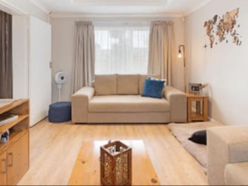 A comfortable living room featuring light-toned laminate flooring and neutral wall finishes, providing a functional and inviting space for relaxation.