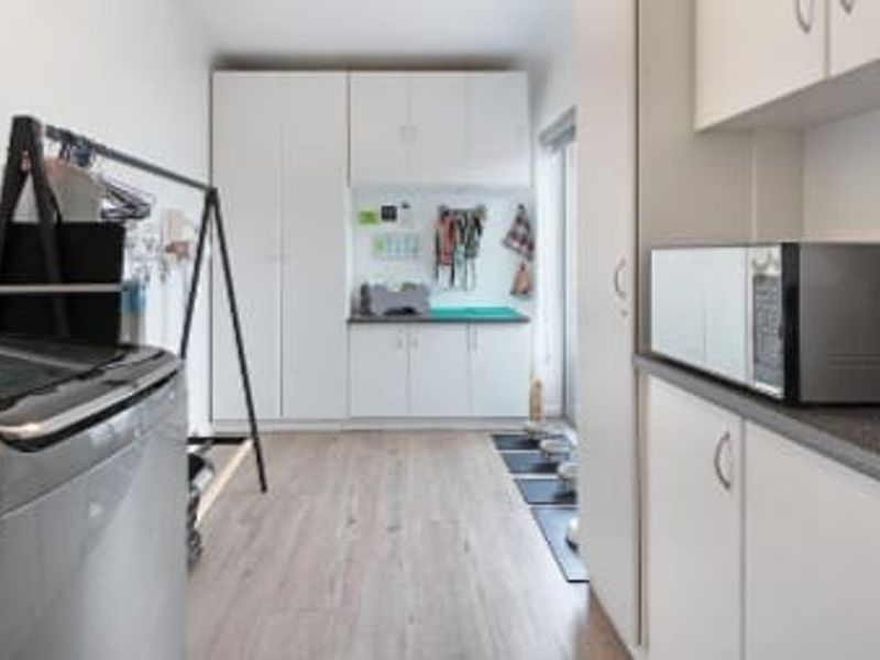 A functional laundry room featuring ample built-in cabinetry, laminate flooring, and a dedicated countertop workspace for household tasks.