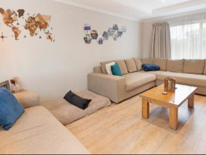 A comfortable living room featuring light-toned laminate flooring and neutral wall finishes, providing a bright and inviting space for relaxation.