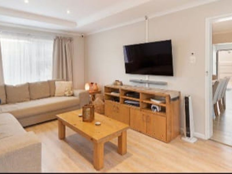 A well-maintained living room featuring light laminate flooring, recessed ceiling lighting, and neutral wall tones, providing a comfortable and inviting space.