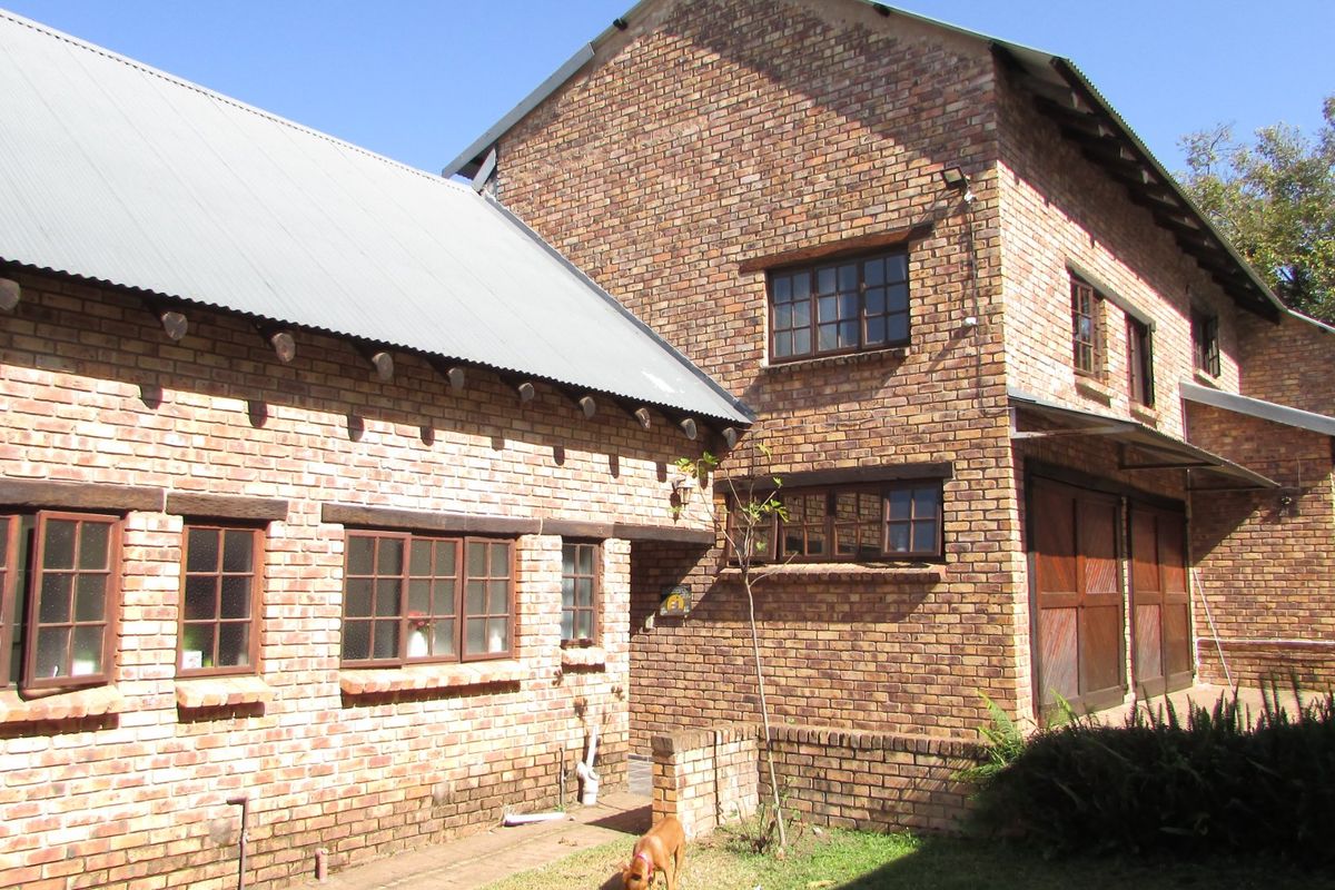 Rear view of a double-story face brick house featuring a corrugated metal roof and timber-framed windows.
