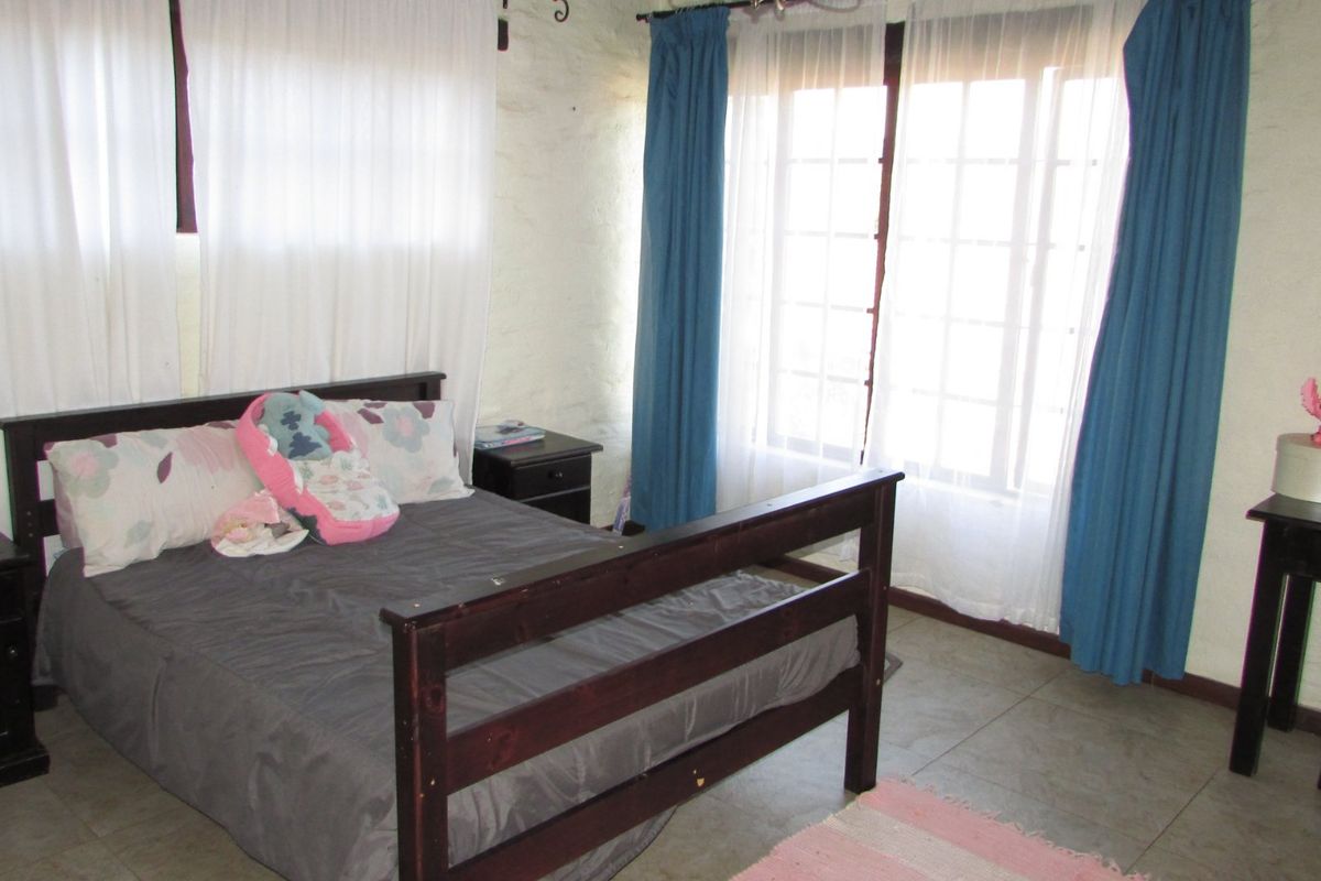 A bedroom featuring tiled flooring, textured walls, and large windows allowing natural light.