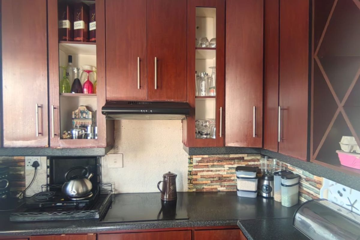 A functional kitchen featuring dark wood cabinetry, integrated appliances, and a stone-look backsplash, offering a classic layout with ample storage space.