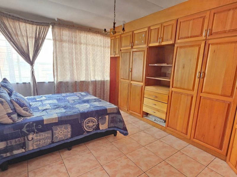 A bedroom featuring extensive built-in wooden cabinetry and tiled flooring, offering ample storage space.