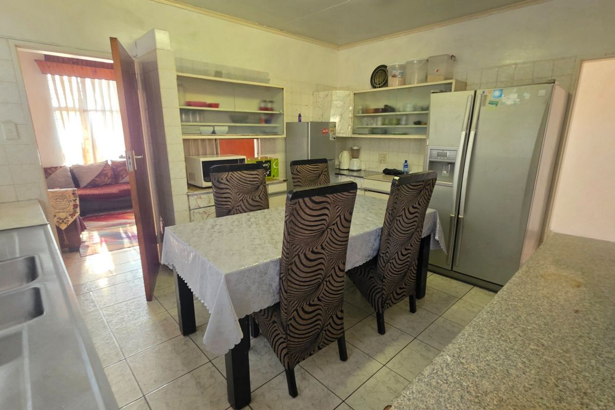 A functional kitchen featuring tiled flooring, built-in cabinetry, and a double stainless steel sink, offering potential for modernization and layout optimization.