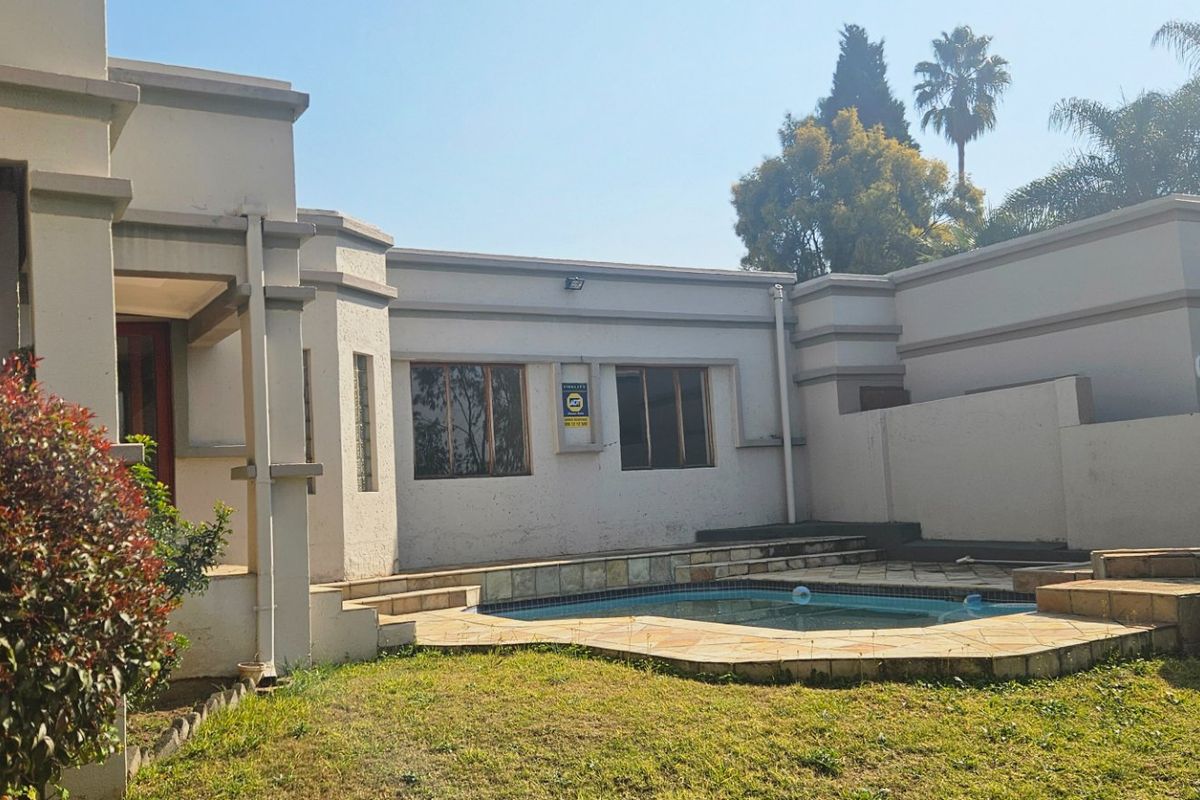 Rear exterior view of the townhouse featuring a private swimming pool, stone patio area, and landscaped garden space.