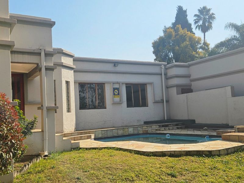 Rear exterior view of the townhouse featuring a private swimming pool, stone patio area, and landscaped garden space.