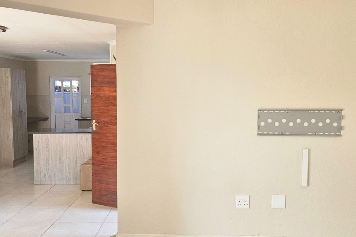 A view from a living area looking through a doorway into a kitchen space with tiled flooring and neutral wall finishes.