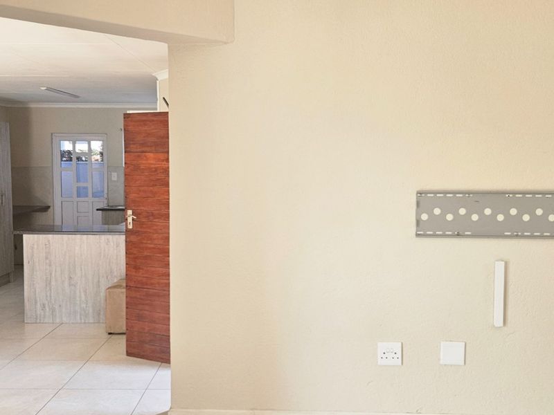 A view from a living area looking through a doorway into a kitchen space with tiled flooring and neutral wall finishes.