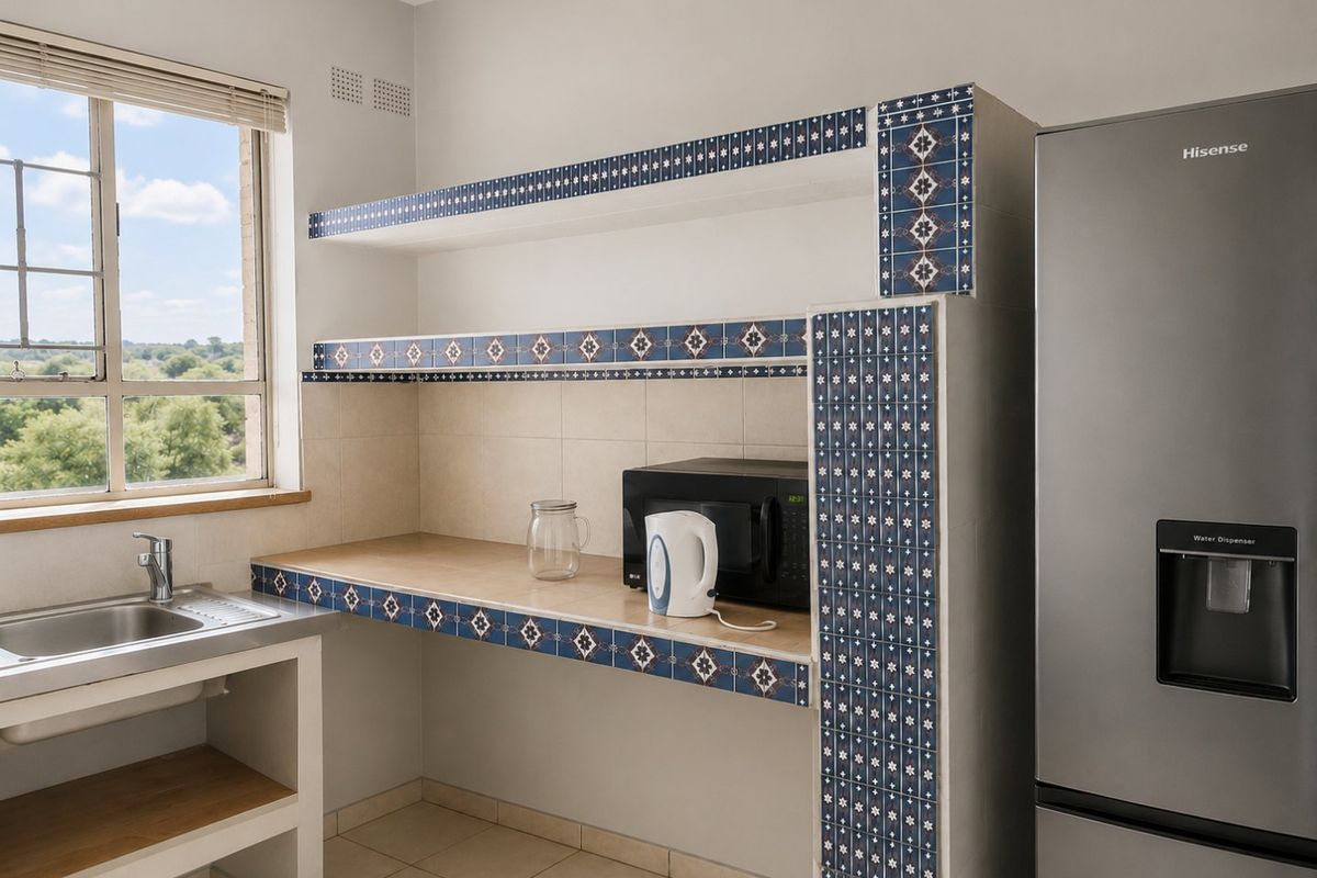 A functional kitchen area featuring built-in tiled shelving, a stainless steel sink, and a window providing natural light and scenic views.