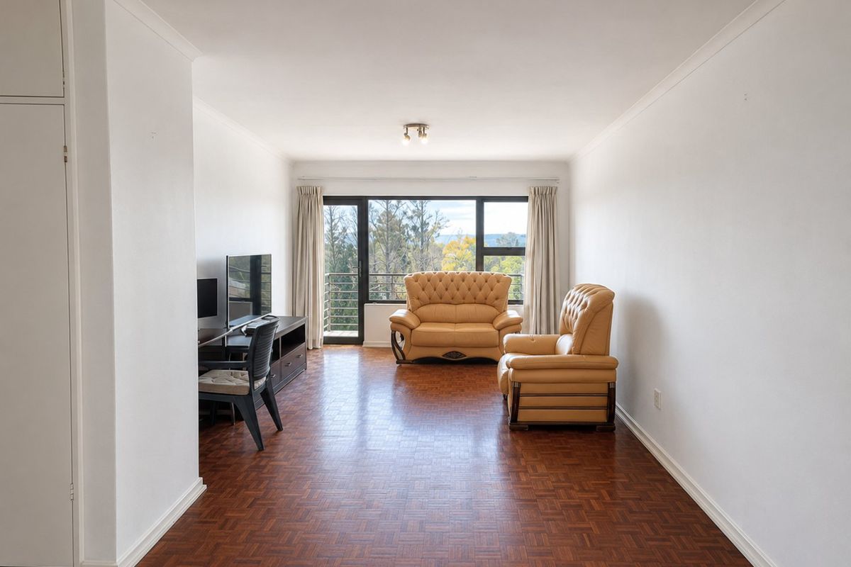 A bright living room featuring classic parquet flooring, a built-in cupboard, and a large sliding glass door providing natural light and outdoor views.