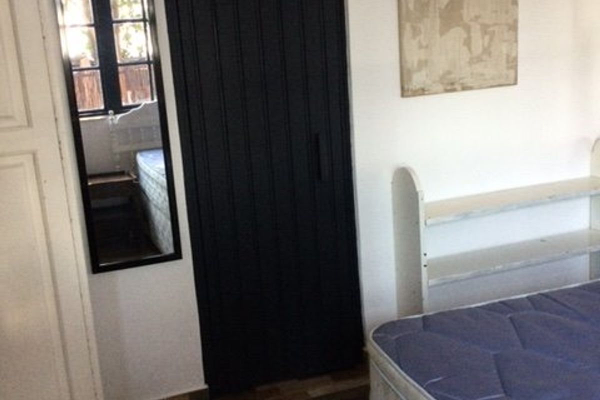 A bedroom featuring tiled flooring, a built-in cupboard, and a window, providing a functional space with basic finishes.