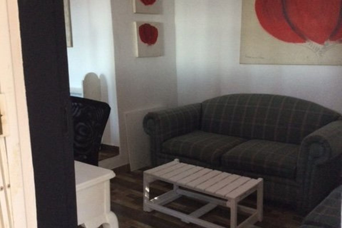 A cozy living room area featuring tiled flooring and exposed ceiling beams, providing a comfortable space for relaxation.