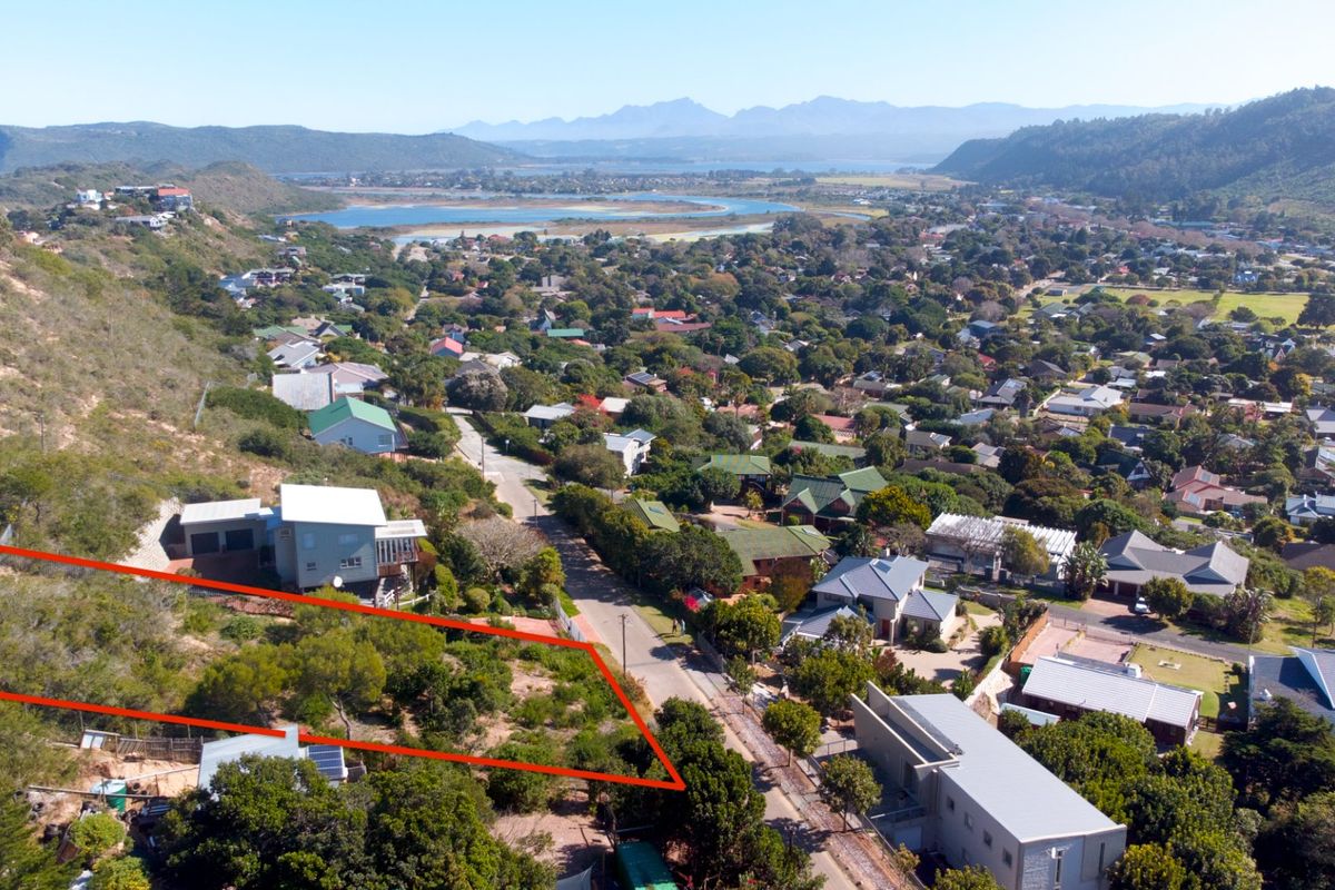 Aerial view of a vacant residential plot situated on a hillside, offering expansive views of the surrounding neighborhood and landscape.