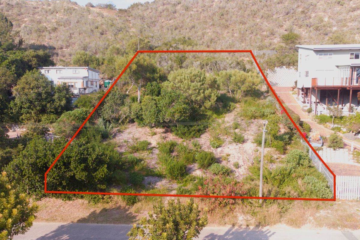 An aerial view of a vacant residential plot featuring natural vegetation and defined boundary lines, situated in a hillside neighborhood.