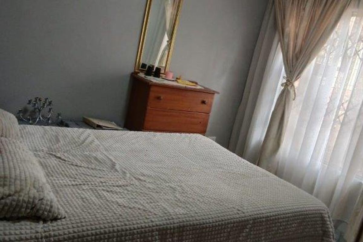 A bedroom featuring tiled flooring and neutral grey walls, providing a functional and comfortable sleeping space.