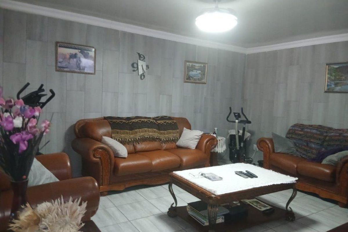 A living room featuring tiled flooring, coved ceilings, and a central ceiling fan, providing a functional and comfortable space for relaxation.