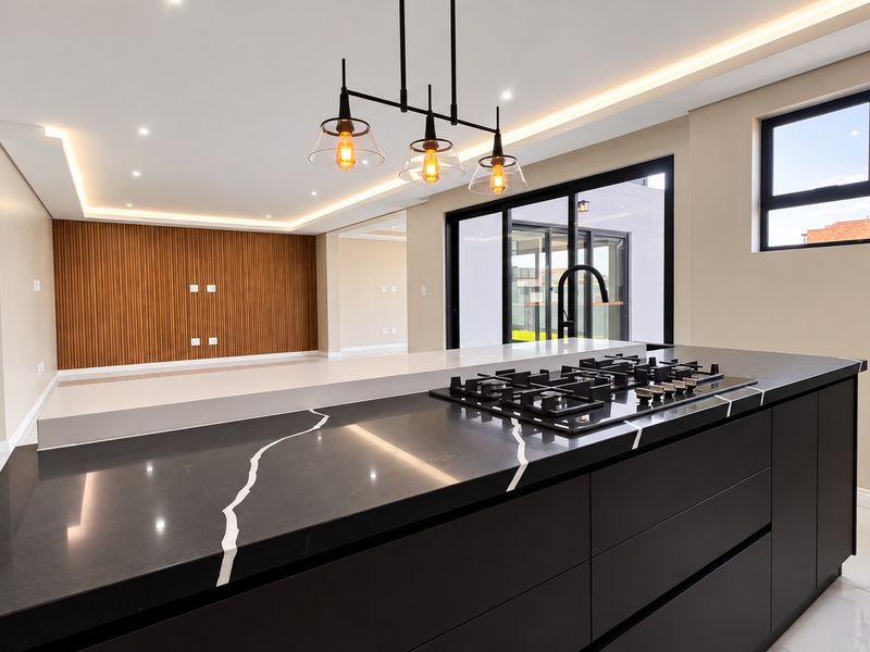 Modern open-plan living area featuring a sleek kitchen island with gas cooktop, stone countertops, and elegant feature slat wall with recessed lighting.