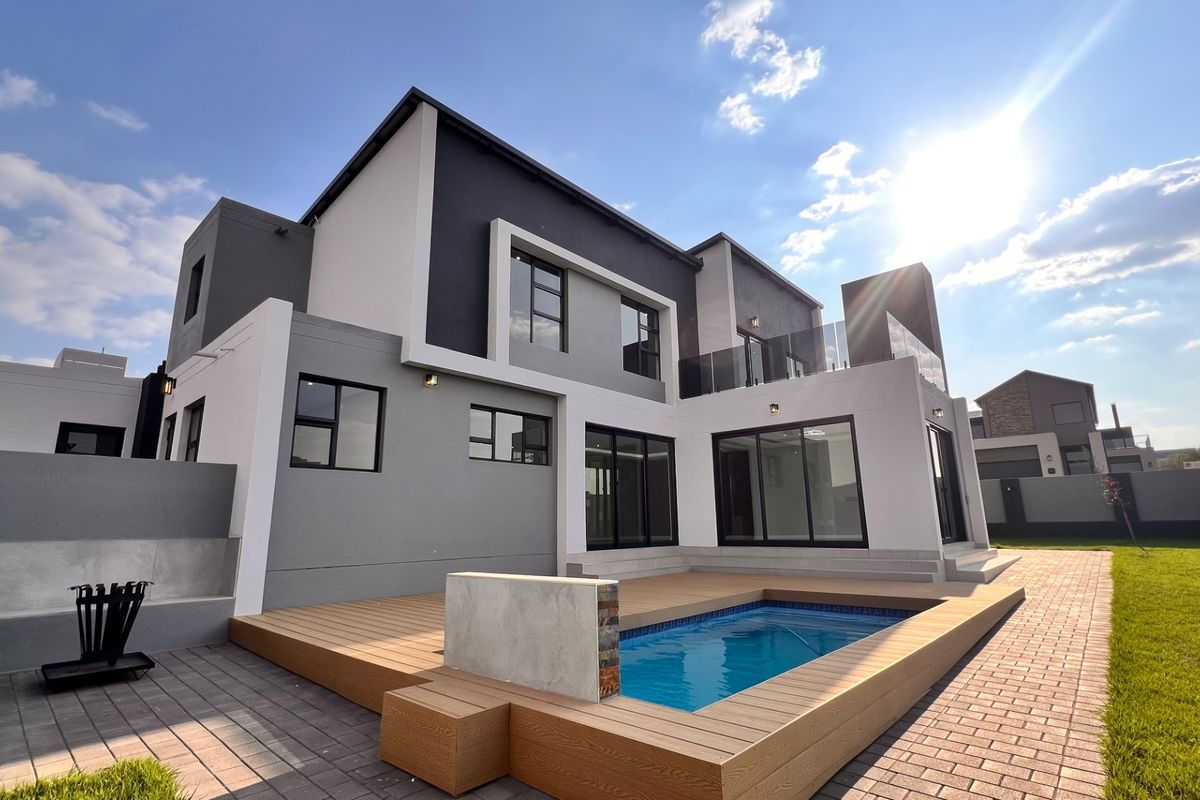 Modern double-story rear elevation featuring a swimming pool, composite decking, paved patio area, and large sliding glass doors opening to the garden.