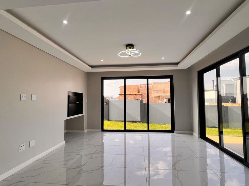 Spacious, modern living area featuring large sliding glass doors, polished porcelain tiles, recessed ceiling lighting, and a built-in fireplace.