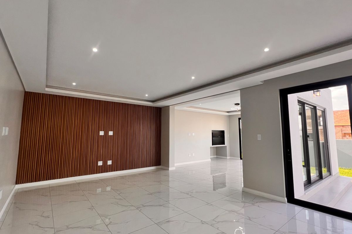 Spacious, modern living area featuring polished porcelain tiles, a contemporary slatted wood feature wall, recessed lighting, and large sliding doors opening to the exterior.