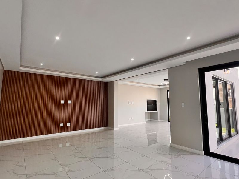 Spacious, modern living area featuring polished porcelain tiles, a contemporary slatted wood feature wall, recessed lighting, and large sliding doors opening to the exterior.