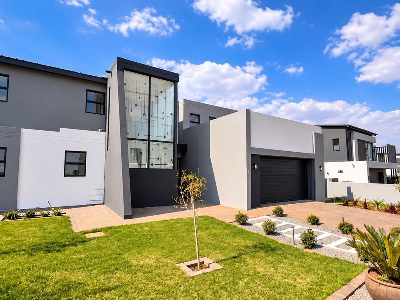 Modern double-story residential property featuring a contemporary facade, double garage, paved driveway, and well-maintained landscaped garden.