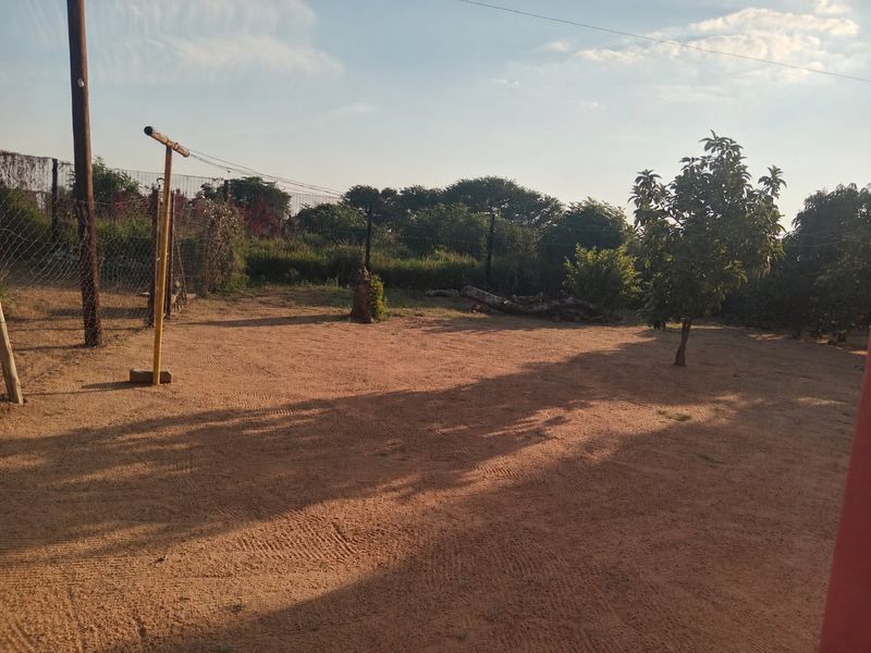 A large, open garden area featuring wire mesh fencing and a metal clothesline pole, offering significant potential for landscaping and outdoor development.
