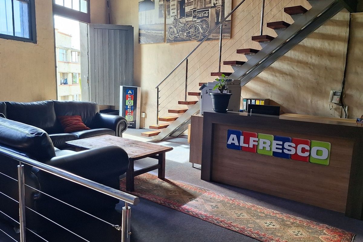 A spacious commercial reception area featuring an open staircase, large windows providing natural light, and a built-in reception desk.