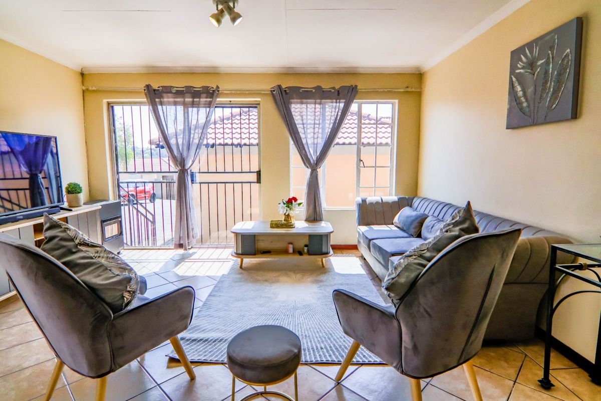 A comfortable living room featuring tiled flooring, a built-in fireplace, and direct access to an outdoor area through a sliding security door.