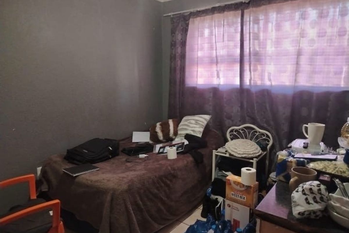 A bedroom featuring tiled flooring and curtain rails, currently utilized as a living space.