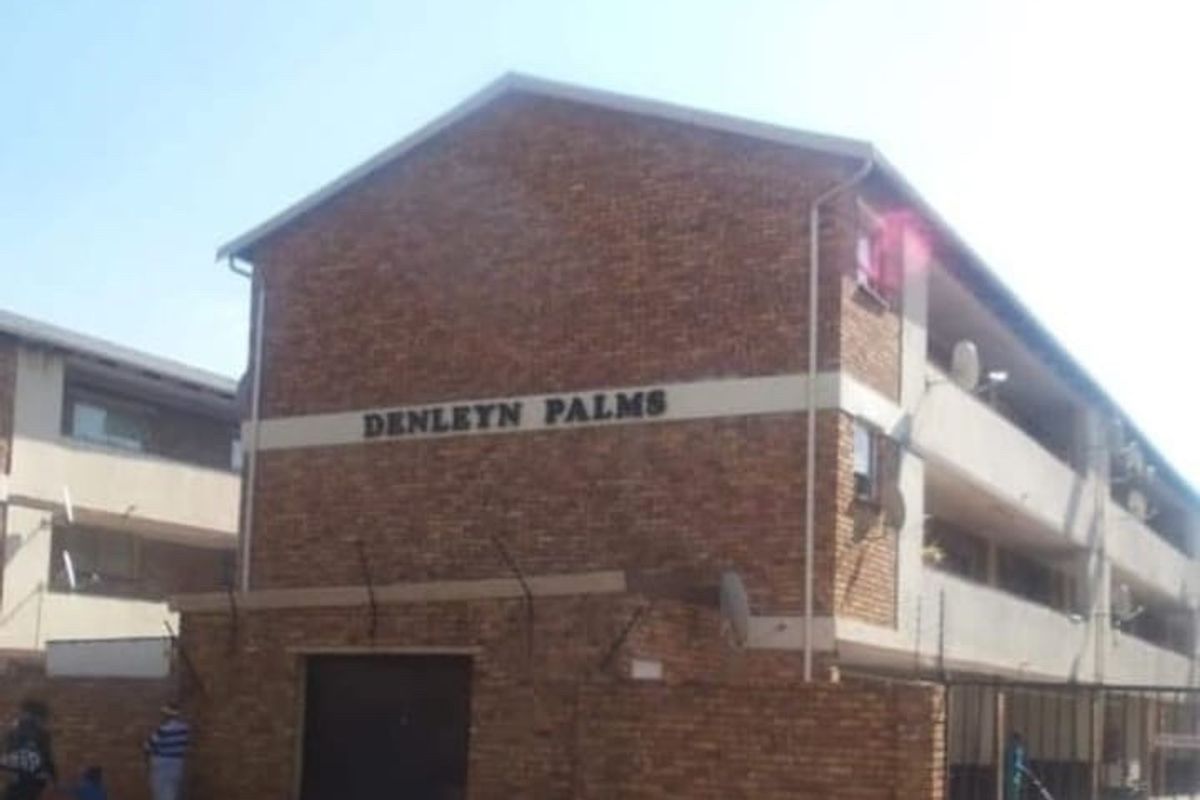 Street view of the Denleyn Palms apartment complex, featuring a face brick facade, perimeter wall, and secure gated entrance.