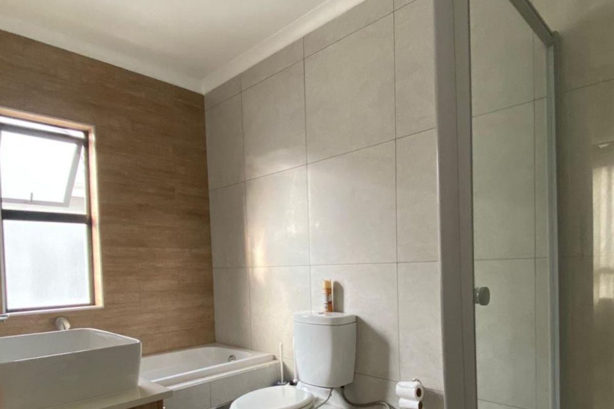 Modern bathroom featuring a built-in bathtub, separate shower enclosure, toilet, and vanity basin with neutral tiled finishes.