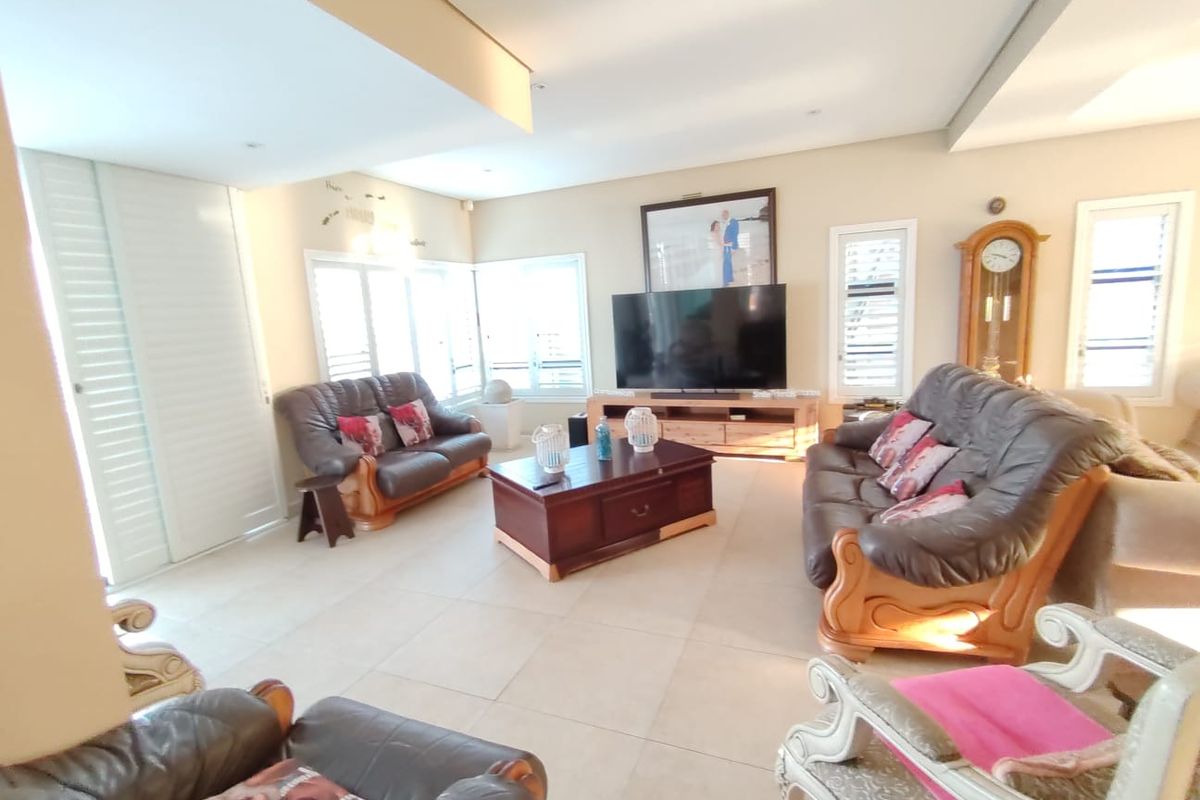 Spacious living room featuring neutral tiled flooring, recessed downlighting, and plantation shutters, offering a bright and comfortable area for relaxation.
