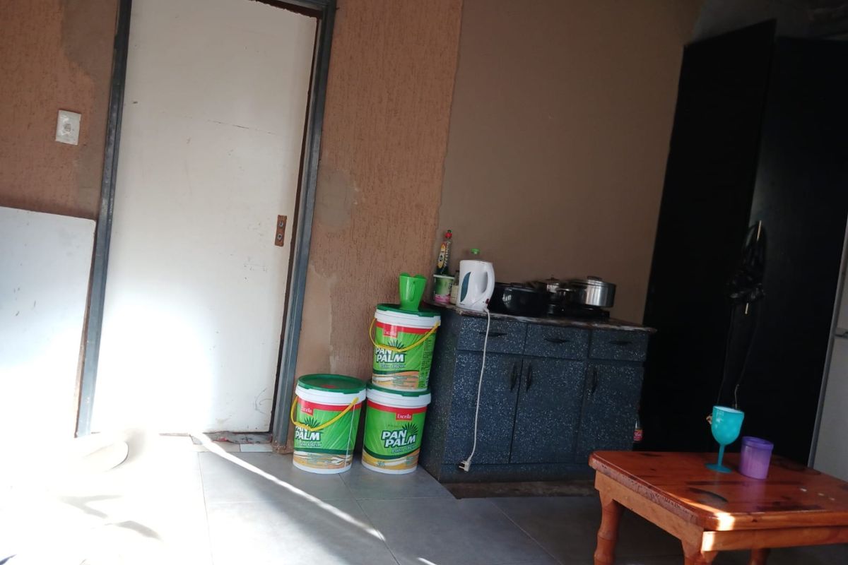 A small kitchen area featuring basic built-in cabinetry and tiled flooring, currently requiring wall finishing and general maintenance to improve the space.